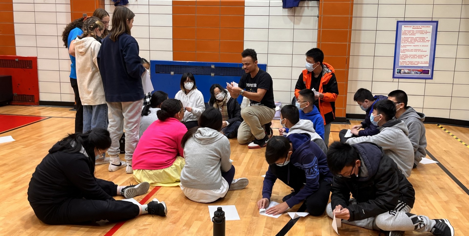 Man with students making paper airplanes. 