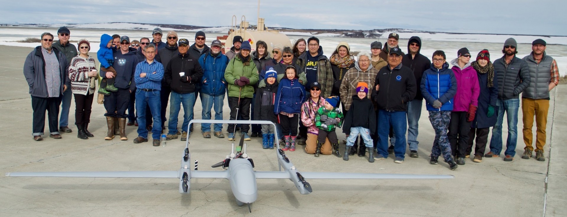 Image curtesy of the Ikaaġvik Sikukun (Ice Bridges) project Image of people in Artic standing behind a drone plane.