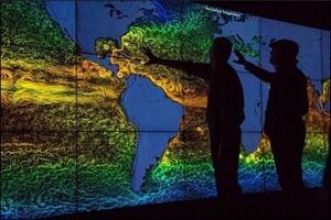 Photo of climate change map with two dark figures pointing towards the image