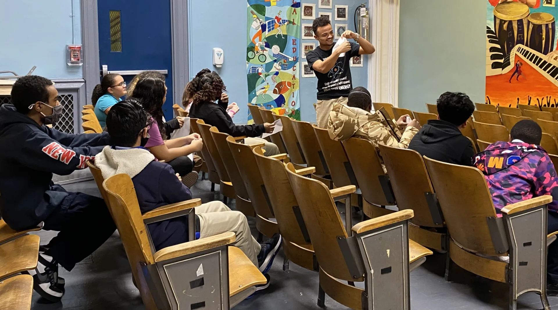 Man showing students how to make paper airplanes. 