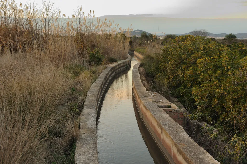 image of small built canal of water through field. 