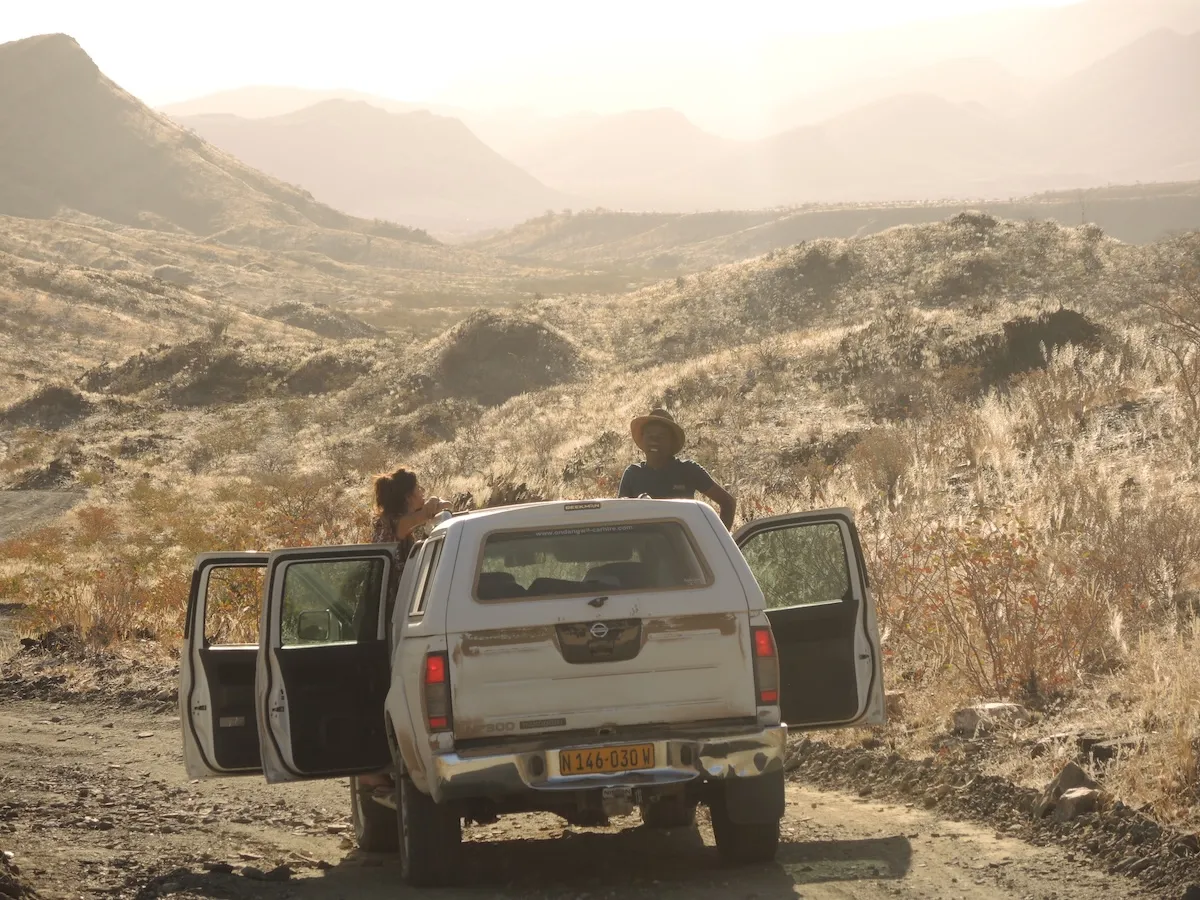 two people in a truck driving in grasslands