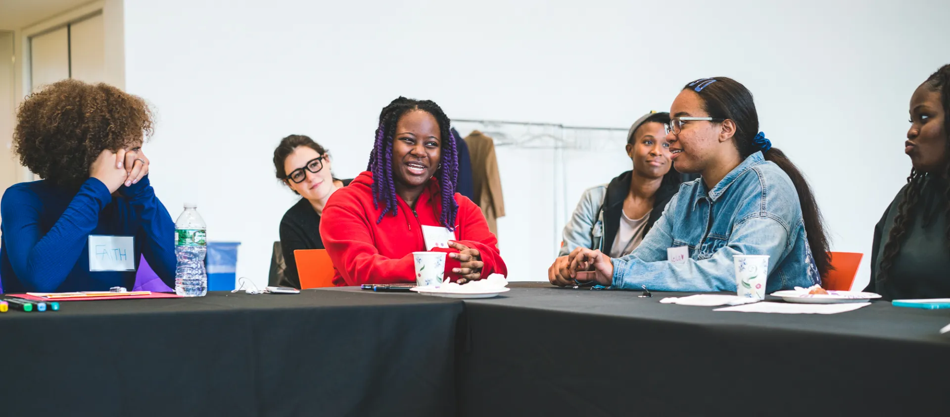 Young women smiling around a conference table. 