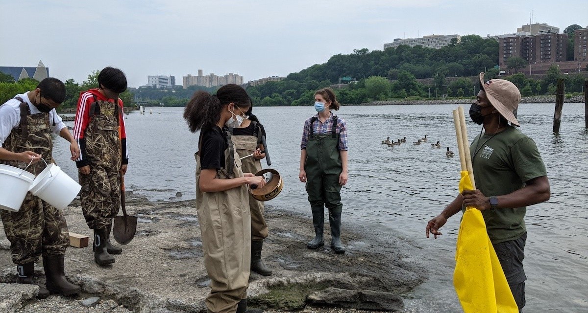Students experimenting in the Harlem River image of students with nets doing experiments by a river.